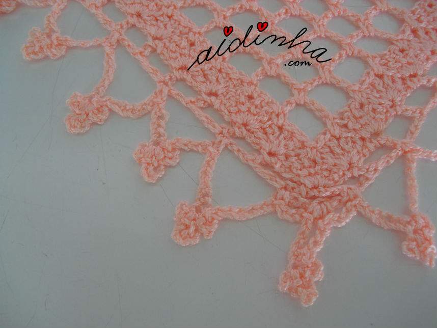 Vista aproximada, da franja de florinhas do baktu, de crochet, cor de salmão