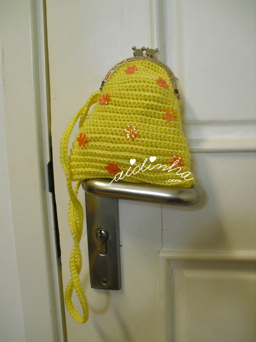 Vista mais aproximada da bolsa infantil, em crochet, amarela com florinhas laranja